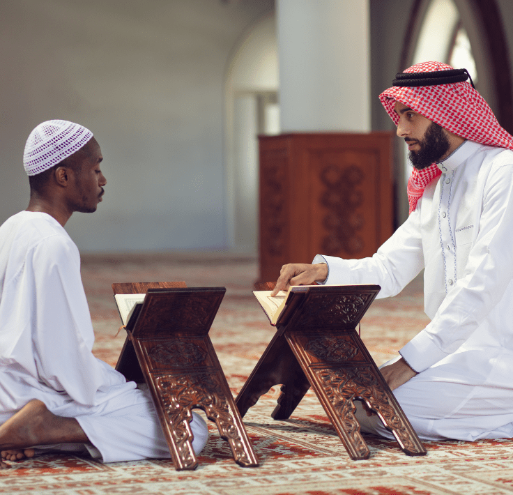 Shahada – Declaración de Fe Dos hombres en una mezquita, uno levantando el dedo índice realizando la Shahada
